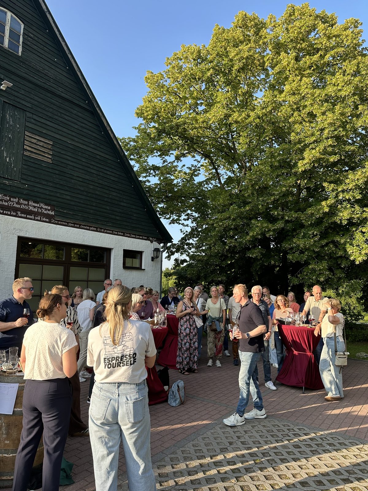 Weinprobe im Abendlicht vor dem Holzgiebel